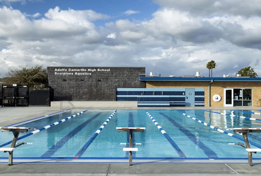 Front-on view of a competitive lap pool featuring a dark masonry wall with "Scorpions Aquatics" signage.