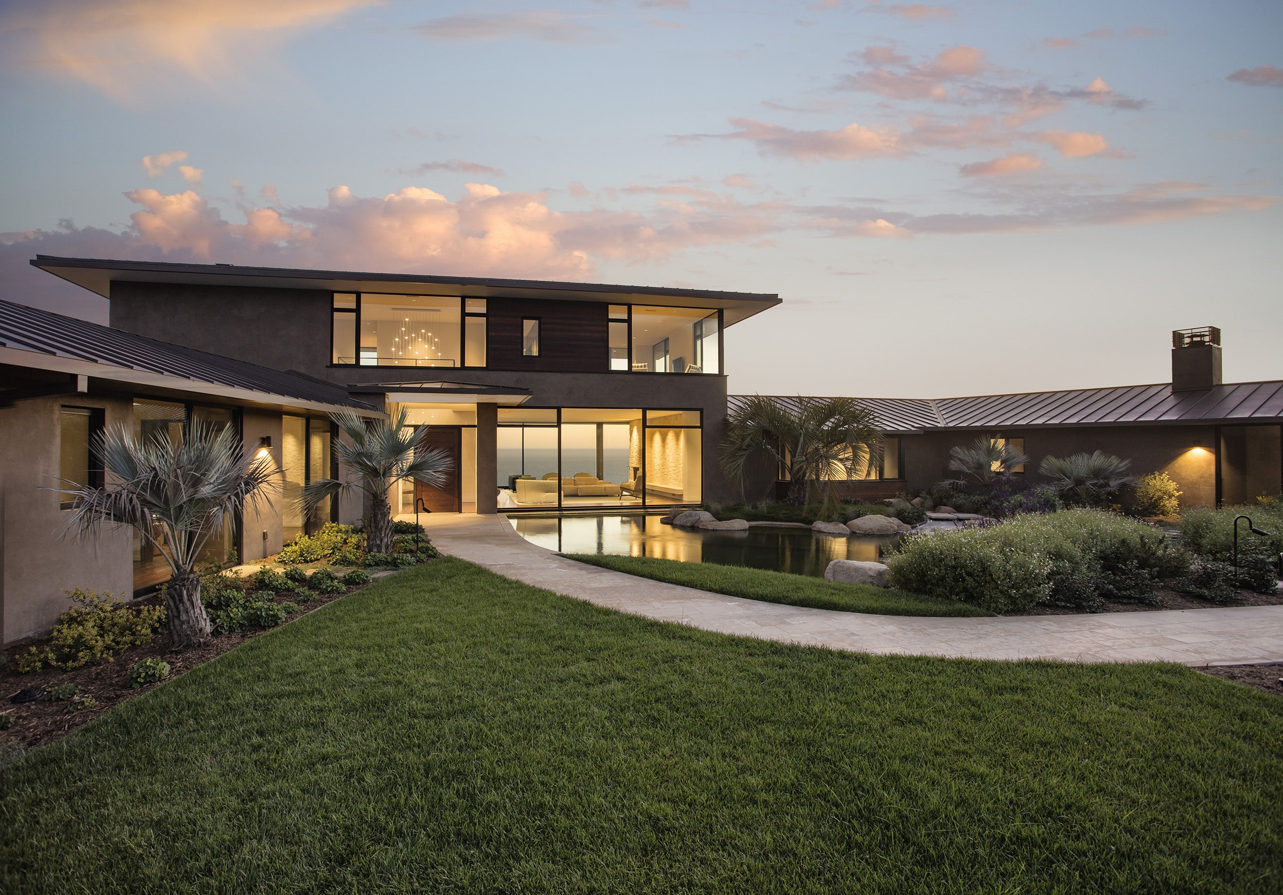 Evening view of a modern courtyard home with warm interior lighting