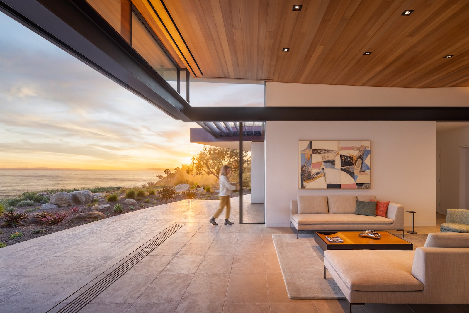 Contemporary coastal residence with retractable glass doors connecting living space to ocean-view patio