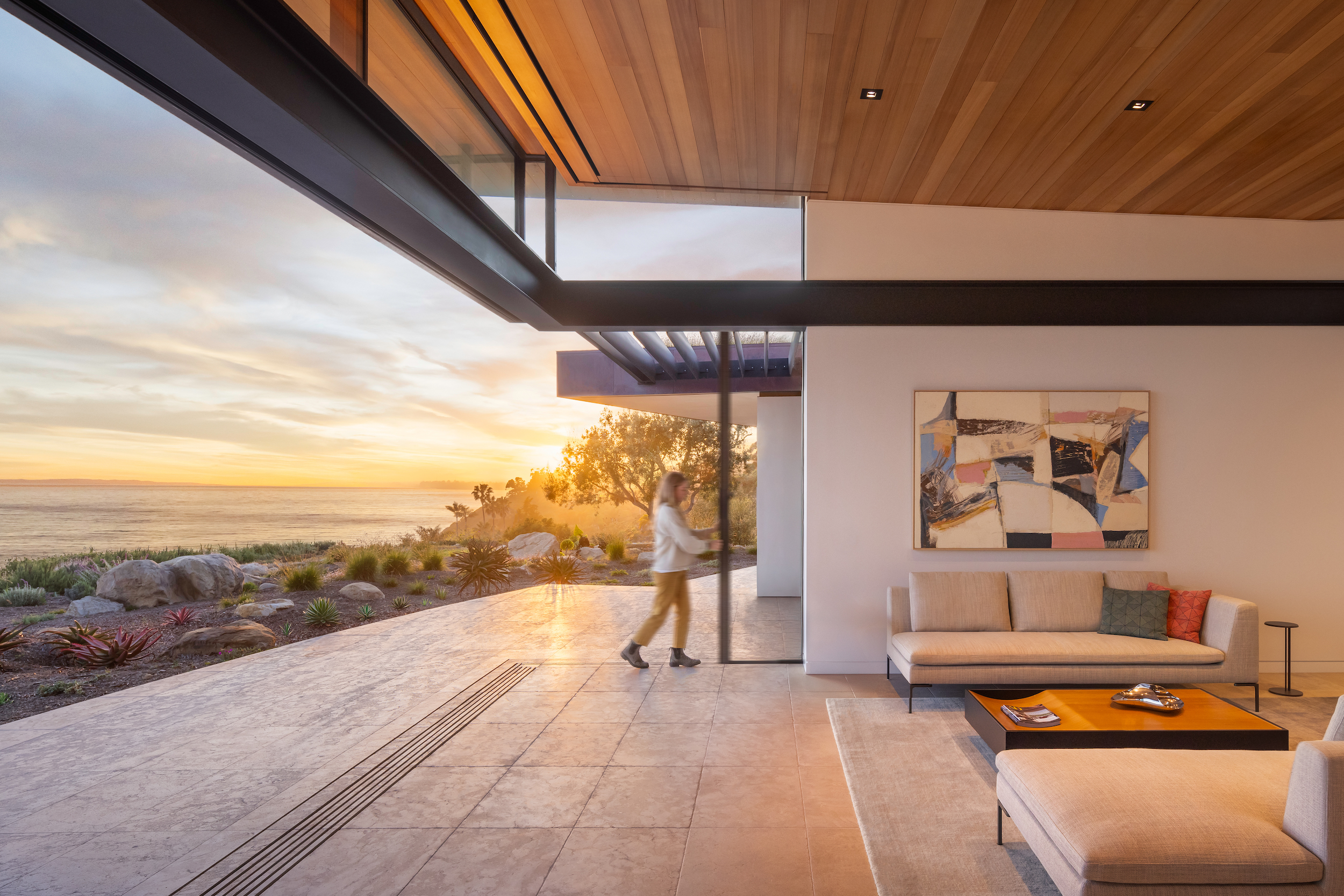 Contemporary coastal residence with retractable glass doors connecting living space to ocean-view patio
